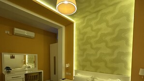 A hotel room with a large bed, a desk, a chair, a mirror, and a wall-mounted air conditioner. - ALBON Park (Berat)