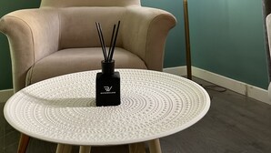 A room with a beige armchair, a round table with a white textured top, a black bottle, and a yellow lamp. - ALBON Park (Berat)