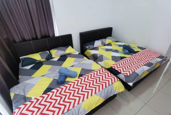 A room with two beds, each with a distinct geometric patterned bedspread.