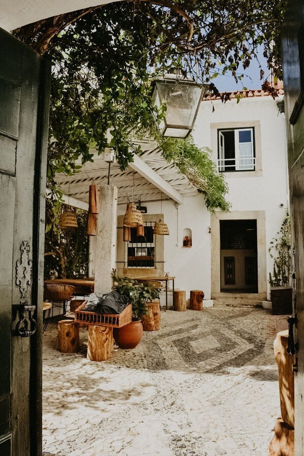 Un patio rústico con una mesa de madera, plantas en macetas y cestas colgantes.