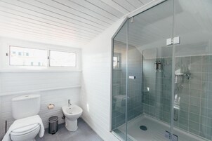 Ein modernes Badezimmer mit einer Duschkabine, weißen Fliesen, einer Toilette und einem Bidet.