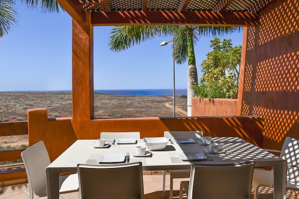 A dining area with a table set for four, overlooking a coastal landscape.