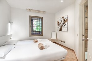 Ein Hotelzimmer mit Bett, Fenster mit Blick, einem Gemälde an der Wand und einer Tür.