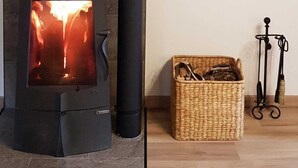 Un foc de llenya encès, una cistella de vimet amb eines i un suport metàl·lic amb una manguera.