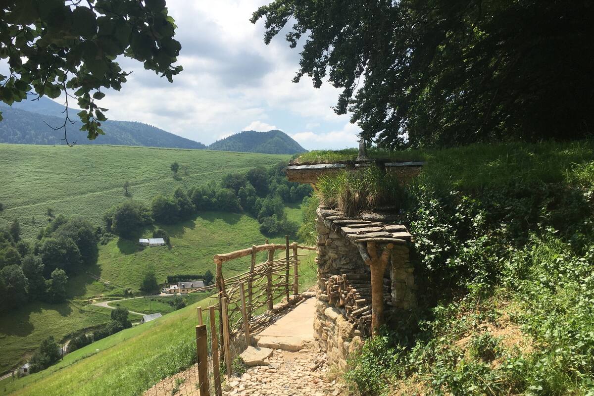 A stone staircase leading to a wooden platform with a view of a green valley and distant mountains.