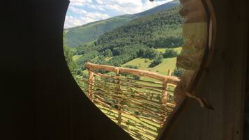 Une fenêtre en forme de cœur donnant sur une vallée verdoyante, le tout bordé d’une clôture en bois.