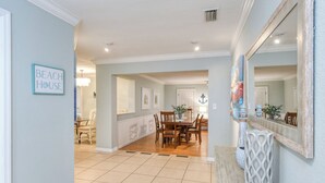 A spacious kitchen with a dining area, a large mirror, and a sign reading "BEACH HOUSE".