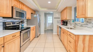 A kitchen with wooden cabinets, stainless steel appliances, a tiled backsplash, and a view to the dining area.