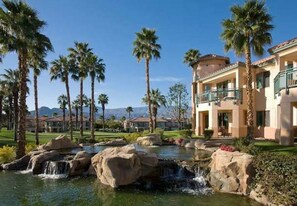 Surrounded by palm trees and a lush lawn, this resort features a pool area with a natural rock formation and a cascading waterfall.