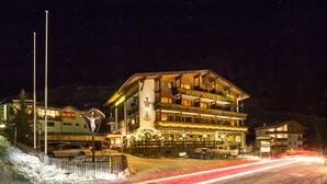 Un hôtel avec un restaurant au rez-de-chaussée, un télésiège visible au loin et un paysage enneigé.