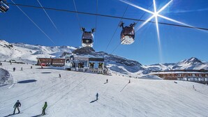A ski resort with a chairlift, a building with a ski lift, and a snowy mountain backdrop. - Hotel Cresta (Samnaun)