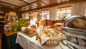 Une table de buffet garnie de différents pains et pâtisseries, un panier en osier et un présentoir en argent pour les plats.