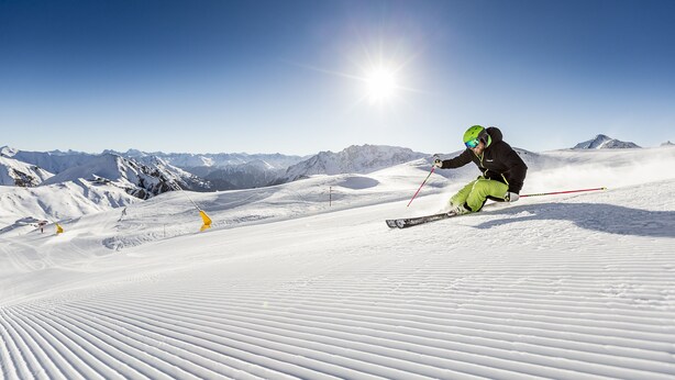 A skier on a snowy slope with mountains in the background and a clear sky. - Hotel Cresta (Samnaun)