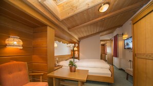 Une pièce de cabane en bois comprenant un lit, une table avec un pot de plante, une chaise et une petite lampe de table.