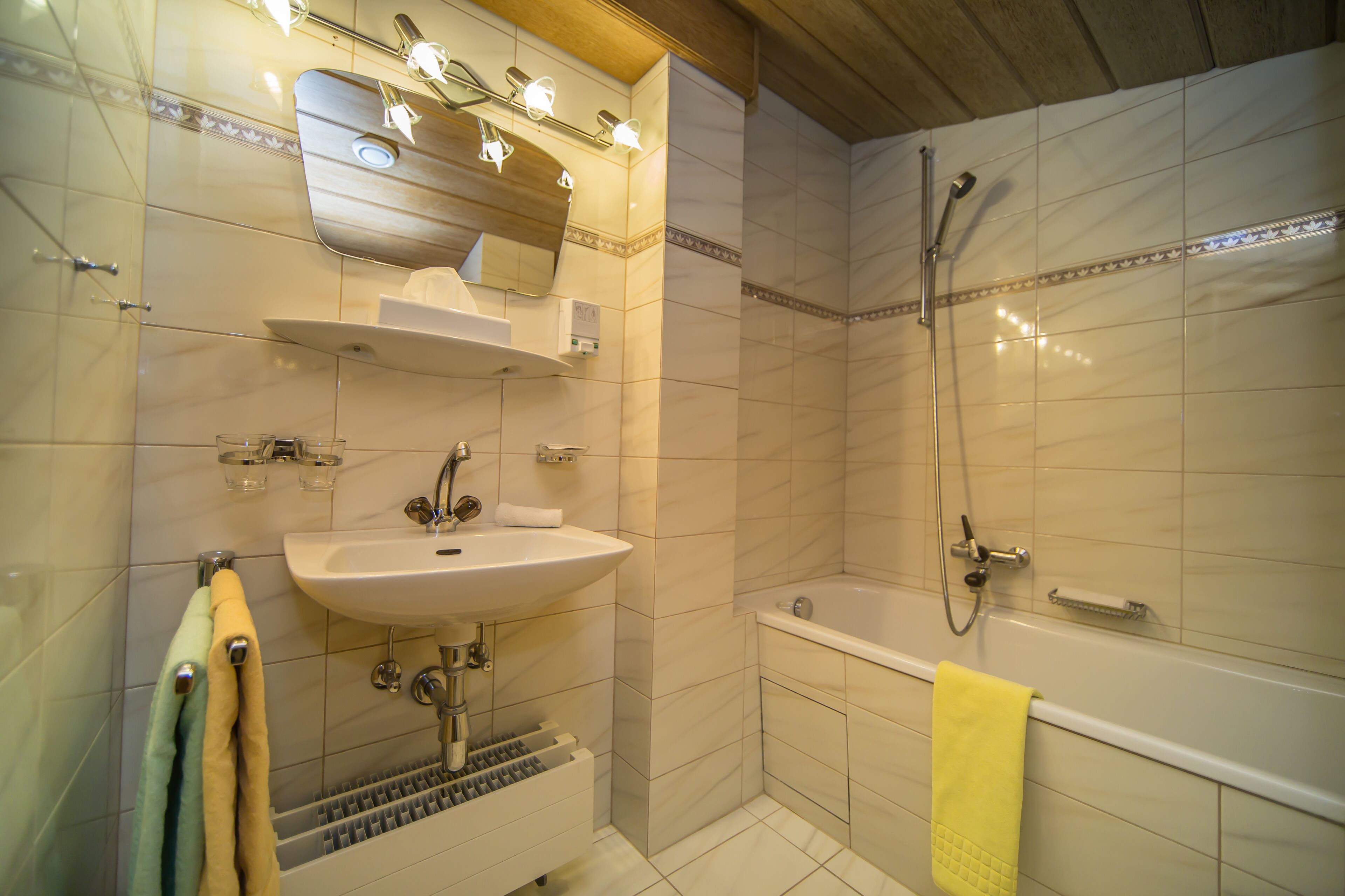 A bathroom with a sink, mirror, towel rack, and shower.