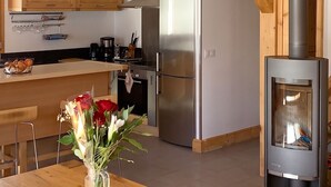 A modern kitchen with wooden beams, a central island, and a wood-burning stove. - Homerez - Chalet in Les Avanchers-Valmorel (Les Avanchers-Valmorel)