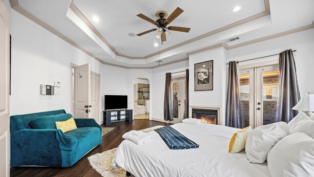 A bedroom with a bed, a blue sofa, a ceiling fan, and a fireplace.