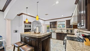 A modern kitchen with dark wood cabinets, granite countertops, and stainless steel appliances.