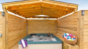 A wooden sauna with a hot tub, a towel, and a basket of colorful towels.
