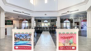 Een ruime atrium met een bar in het midden, diverse zithoeken en bewegwijzering naar het toilet en de speelhal.