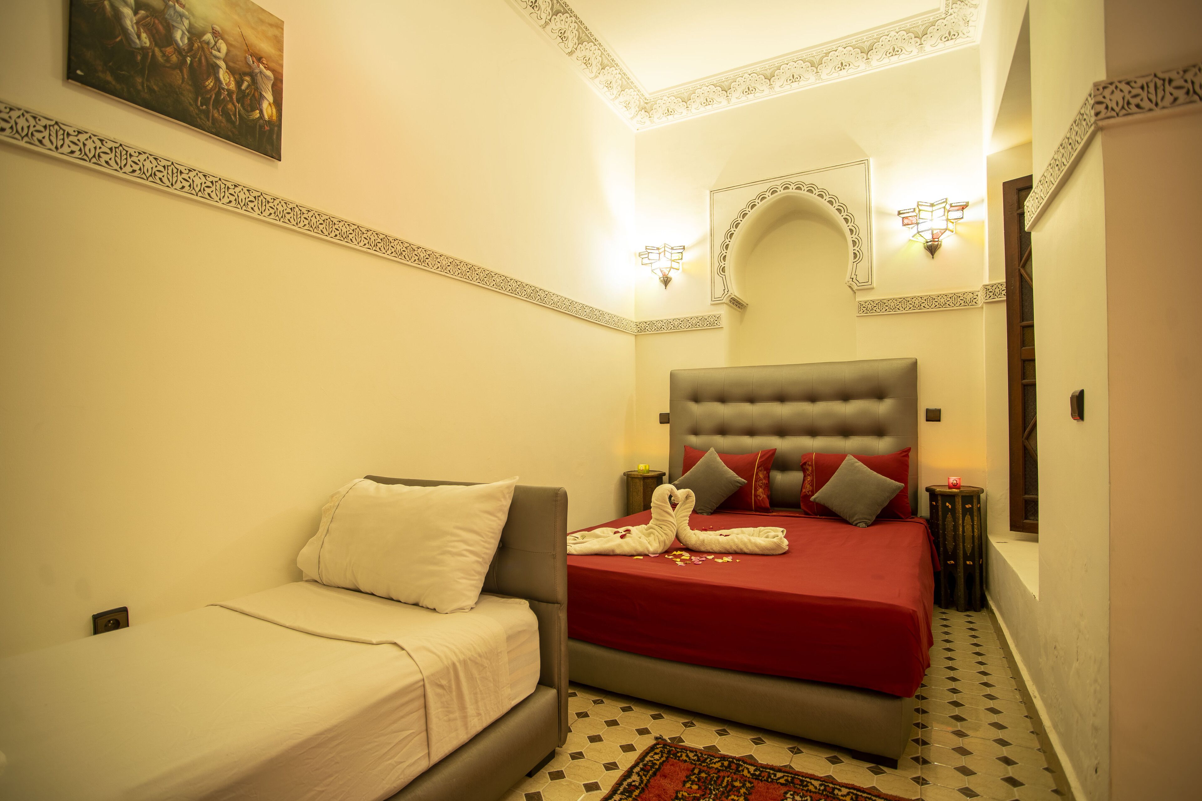 Ein Schlafzimmer mit einem großen Bett, einem kleinen Sofa, einer dekorativen Decke und einer Wandleuchte.