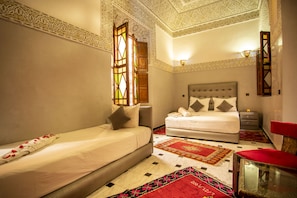 Una camera da letto con un letto, un divano, un comodino e una poltrona rossa.