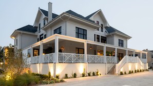 Une grande maison à deux étages, dotée d’un porche et d’un escalier menant à l’étage supérieur.