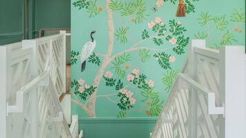 Una escalera con barandillas blancas y un mural en la pared de un árbol con pájaros.