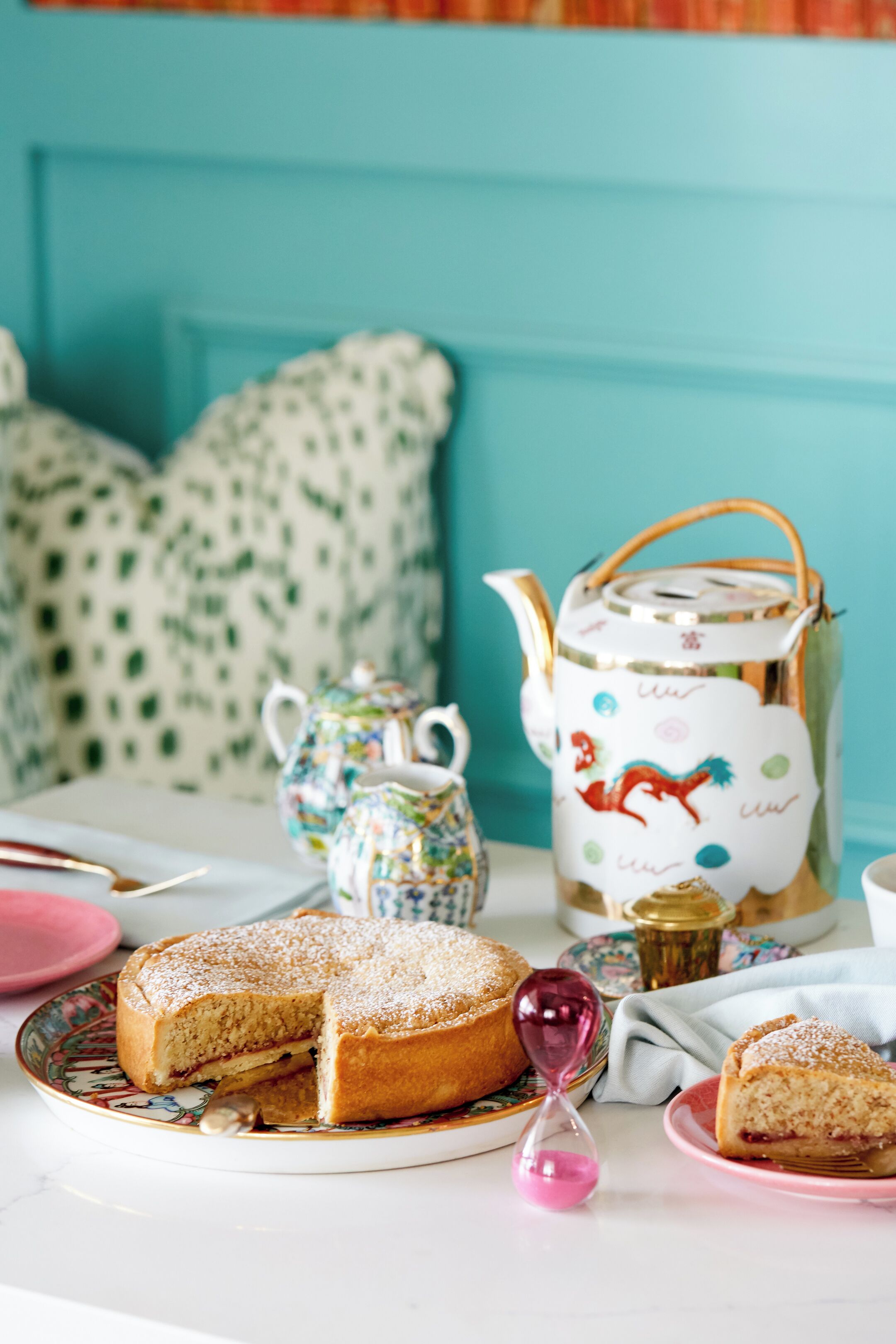 A table with a cake, a teapot, and a jug.