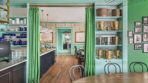 Un espace repas avec une table et des chaises en bois, un buffet proposant divers plats, et un mur orné de tableaux encadrés.