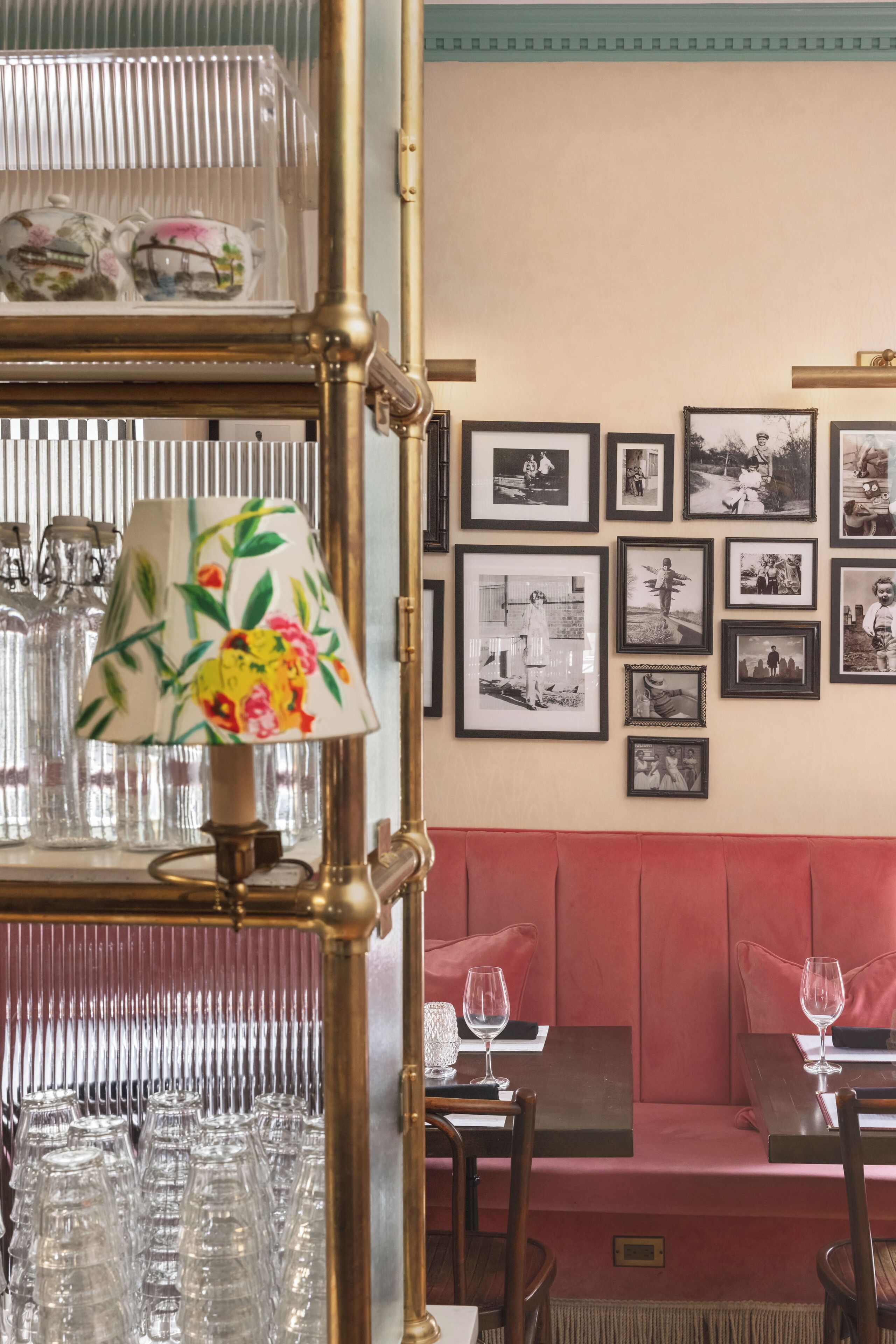 Un espace repas avec des banquettes, un mur décoré de photographies encadrées et une lampe décorative ornée de motifs floraux.