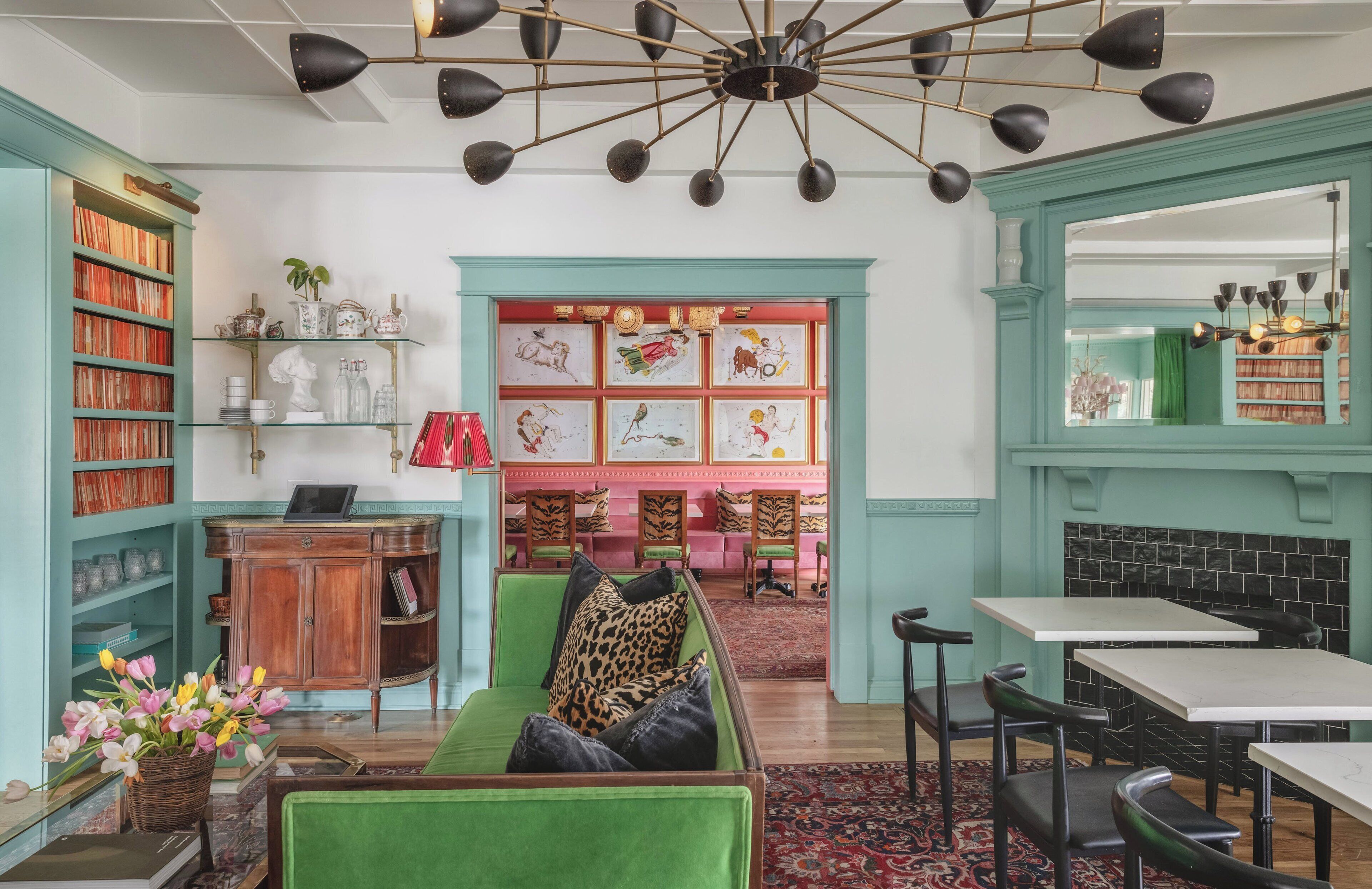 Un rincón acogedor para leer, con un sofá verde, una mesita de madera y una estantería llena de libros y objetos decorativos.