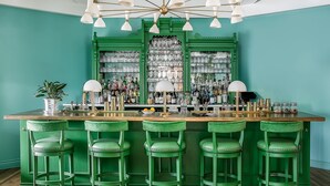 Un espace bar aux couleurs dominantes vertes, avec des murs verts, des tabourets de bar verts et un comptoir de bar vert.
