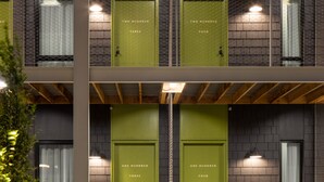 Un bâtiment moderne doté de deux portes vertes portant les inscriptions « Cent trois » et « Deux cent quatre ».