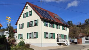 A two-story building with green shutters, a red-tiled roof, and solar panels. - Geiger's apartment in the Laucherttal (Veringenstadt)