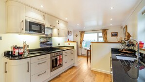 Een moderne keuken met witte kastjes, een zwart aanrecht en houten vloeren.
