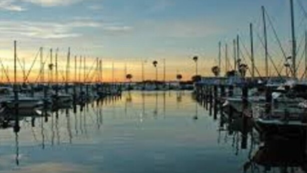 Un port de plaisance où des bateaux sont amarrés dans des eaux calmes, au coucher du soleil.