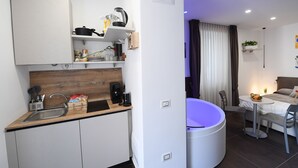 A compact kitchen with a sink, stove, and various utensils. A dining area with a table and chairs is adjacent to the kitchen. - B&B In Centro Storico Salerno (Salerno)