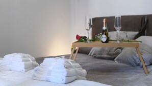 A neatly made bed with a wooden tray holding a bottle, glasses, and a rose. - B&B In Centro Storico Salerno (Salerno)
