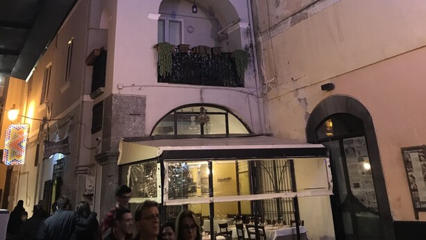 A building with illuminated signs and a balcony with plants. - B&B In Centro Storico Salerno (Salerno)