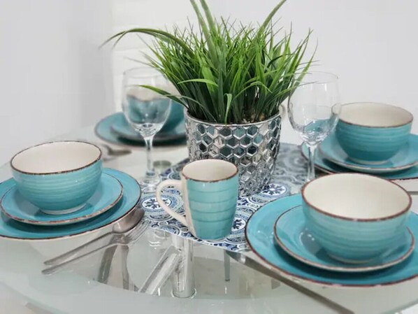 A table set with blue and white plates, a blue mug, and a glass vase with green plants.