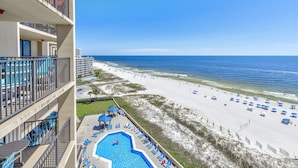 A hotel with a pool, beach view, and multiple balconies.