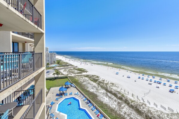 A hotel with a pool, beach view, and multiple balconies.