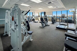 A gym with various exercise equipment, large windows, and a view of the outdoors.