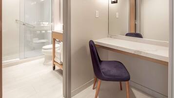 Un baño moderno con cabina de ducha de vidrio, inodoro blanco y tocador con espejo.