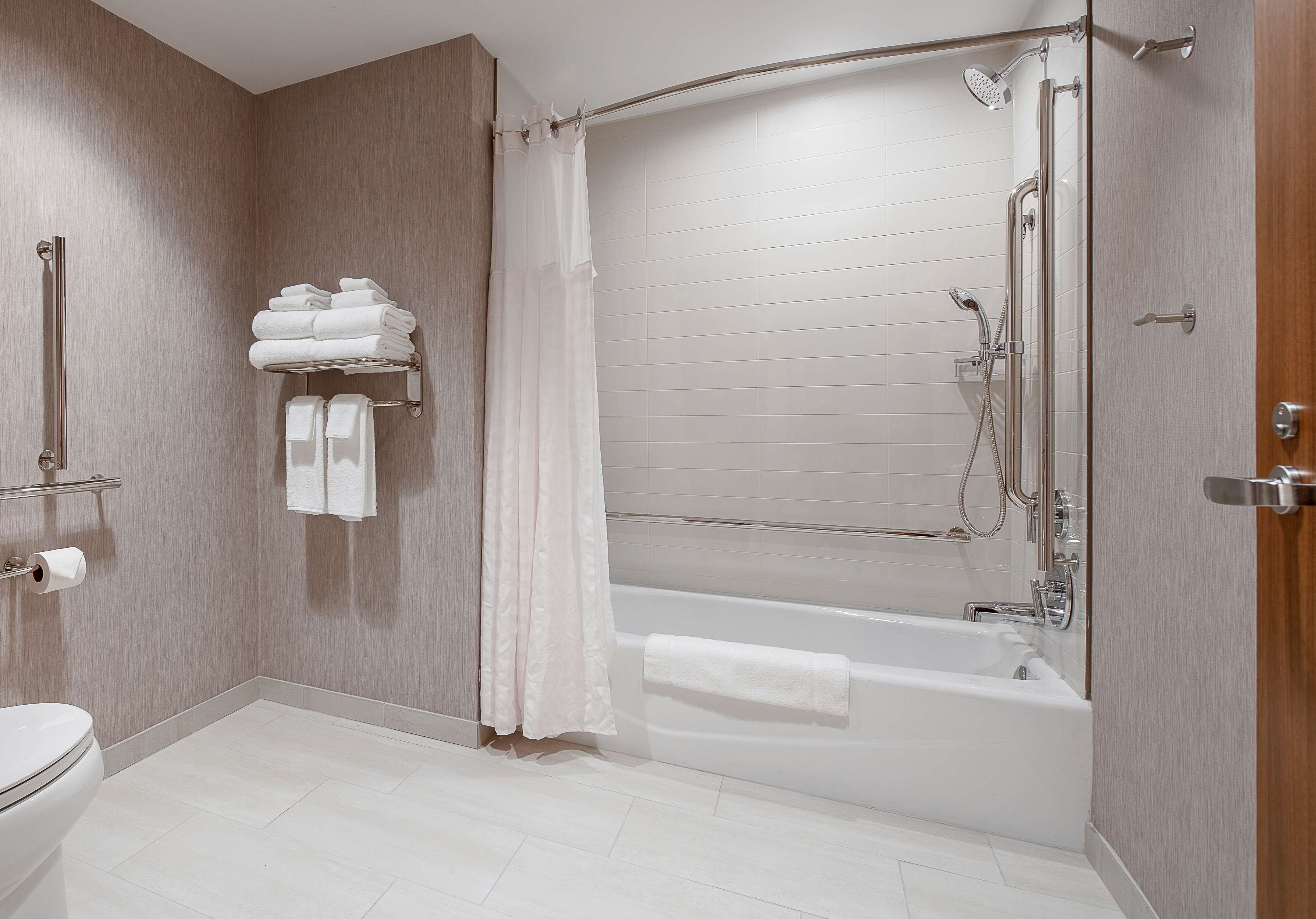A modern bathroom with a bathtub, shower, and toilet.