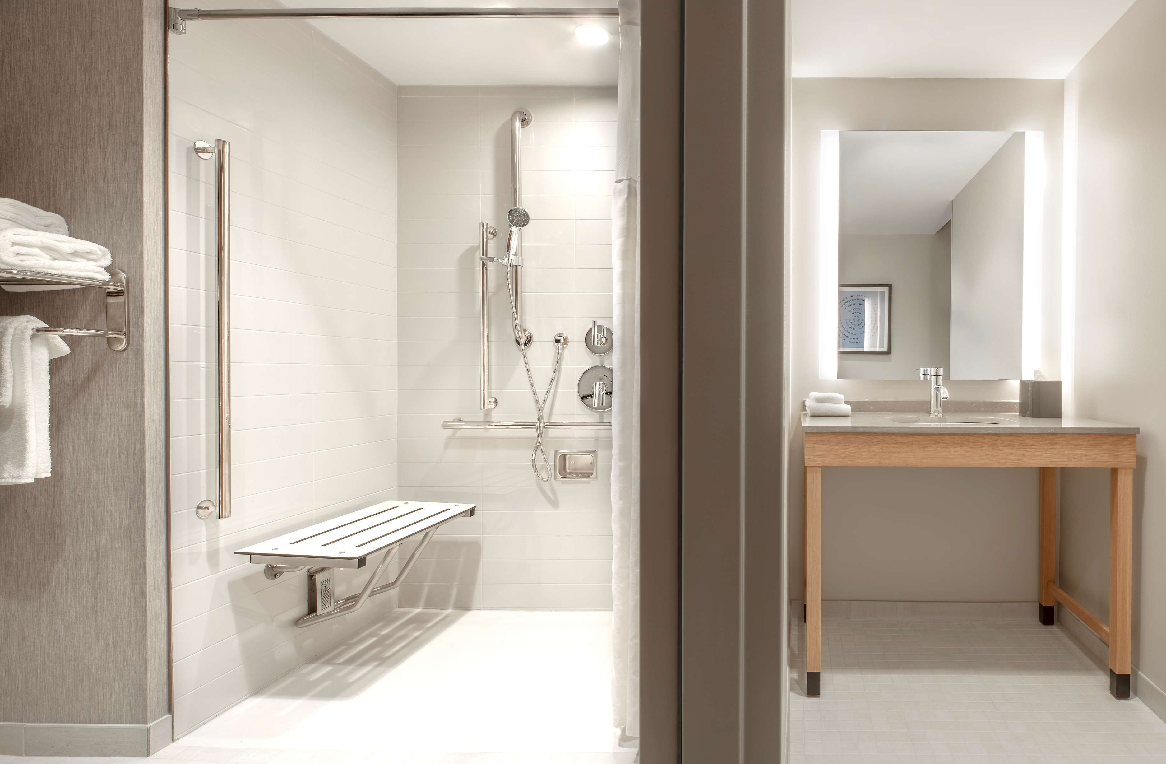 Une salle de bain moderne avec une douche à l’italienne, un meuble-lavabo en bois et une porte de douche en verre.