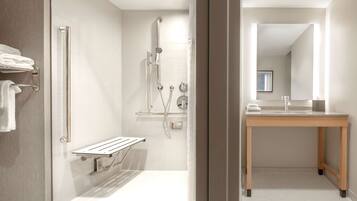Une salle de bain moderne avec une douche à l’italienne, un meuble-lavabo en bois et une porte de douche en verre.