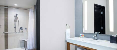Un baño moderno con ducha, lavamanos y espejo.