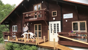 A wooden chalet with a balcony, a sign reading "Alpages", and a small outdoor seating area with two white chairs and a table. - Alpages Madarao (Myoko)
